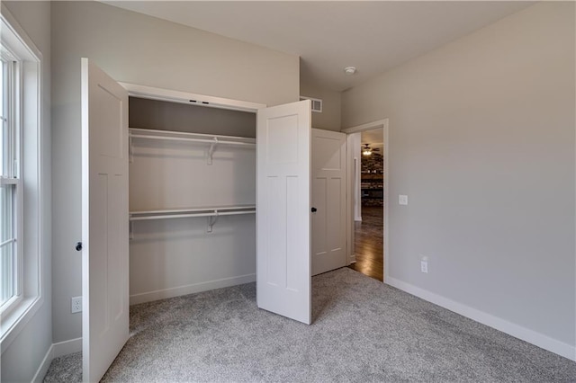 unfurnished bedroom featuring carpet floors, a closet, visible vents, and baseboards