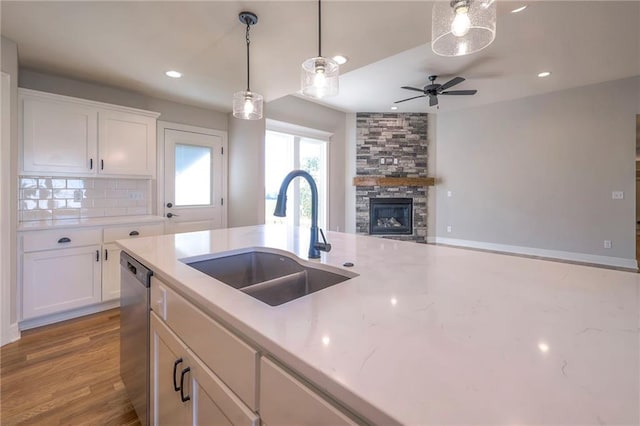 kitchen featuring decorative backsplash, sink, white cabinets, a fireplace, and light hardwood / wood-style floors