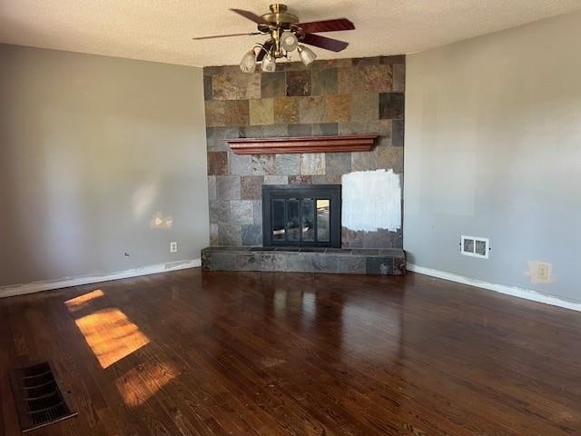 unfurnished living room featuring a textured ceiling, a tiled fireplace, ceiling fan, and hardwood / wood-style flooring