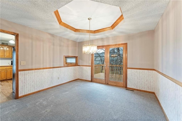 spare room with wallpapered walls, a textured ceiling, a chandelier, and a wainscoted wall