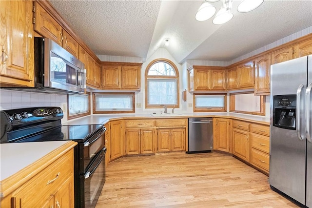 kitchen featuring light wood-type flooring, appliances with stainless steel finishes, light countertops, and a sink