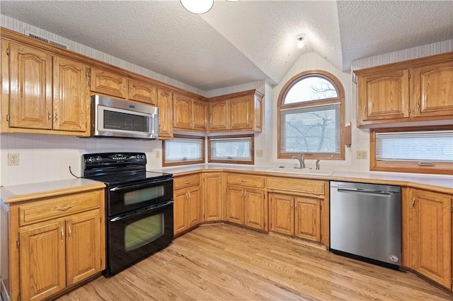 kitchen with light wood finished floors, stainless steel appliances, a sink, and light countertops