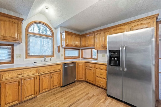 kitchen with brown cabinetry, stainless steel appliances, and a sink