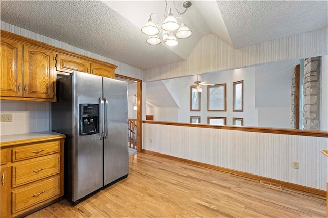 kitchen with wallpapered walls, brown cabinetry, stainless steel fridge with ice dispenser, lofted ceiling, and light wood-style flooring