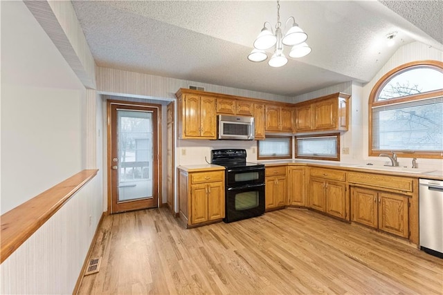 kitchen featuring light wood finished floors, appliances with stainless steel finishes, light countertops, a textured ceiling, and a sink