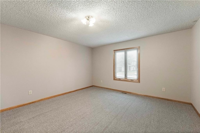 spare room with carpet floors, visible vents, a textured ceiling, and baseboards