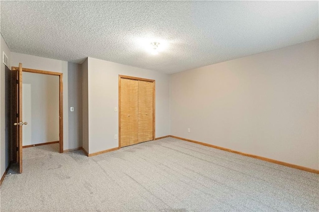 unfurnished bedroom with a closet, visible vents, light carpet, a textured ceiling, and baseboards