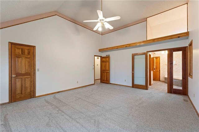 unfurnished bedroom with baseboards, high vaulted ceiling, carpet flooring, and french doors