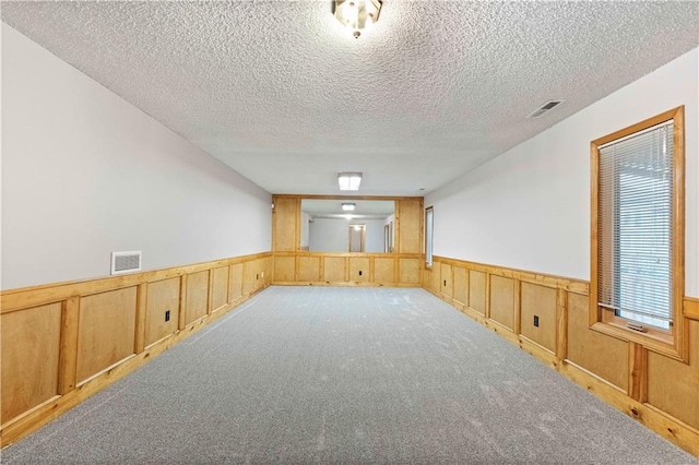 empty room featuring carpet, wainscoting, and visible vents