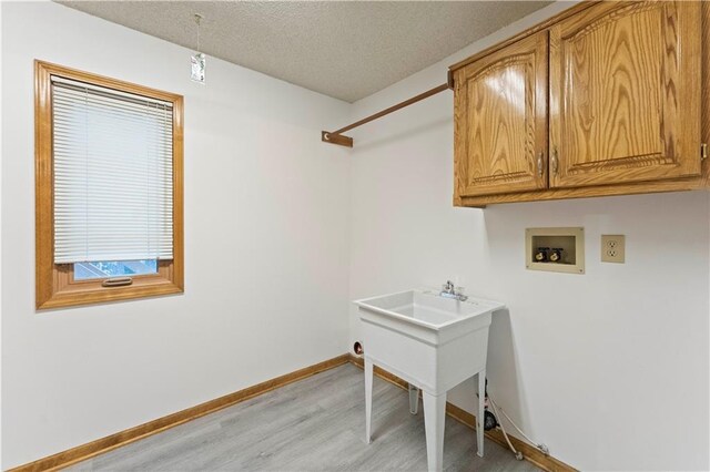 laundry room featuring cabinet space, baseboards, light wood-style flooring, hookup for a washing machine, and a textured ceiling