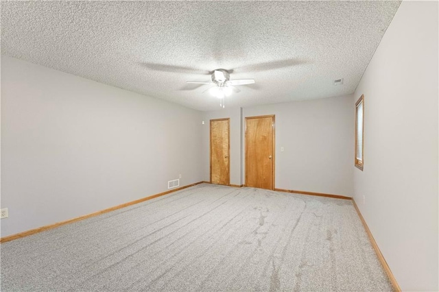 unfurnished bedroom featuring a textured ceiling, ceiling fan, light carpet, visible vents, and baseboards