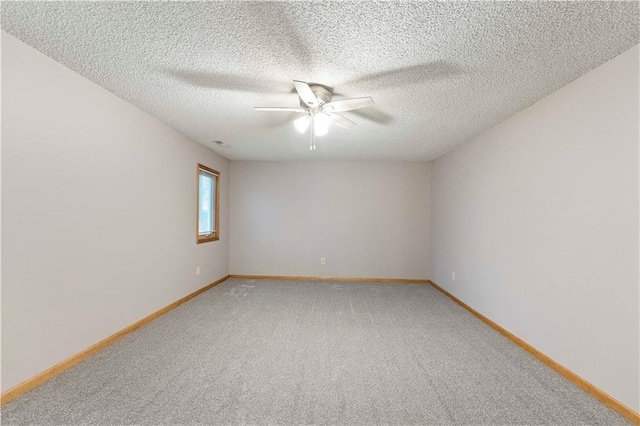 unfurnished room with light carpet, ceiling fan, a textured ceiling, and baseboards