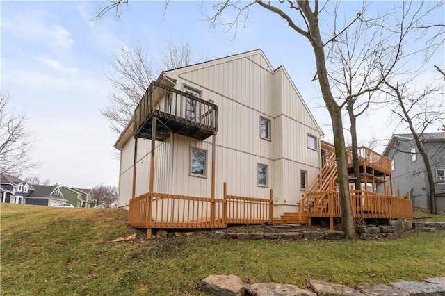 back of house featuring a balcony, a lawn, and a wooden deck