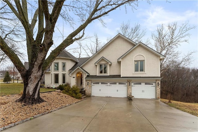 view of front of property with a garage, concrete driveway, stone siding, and stucco siding