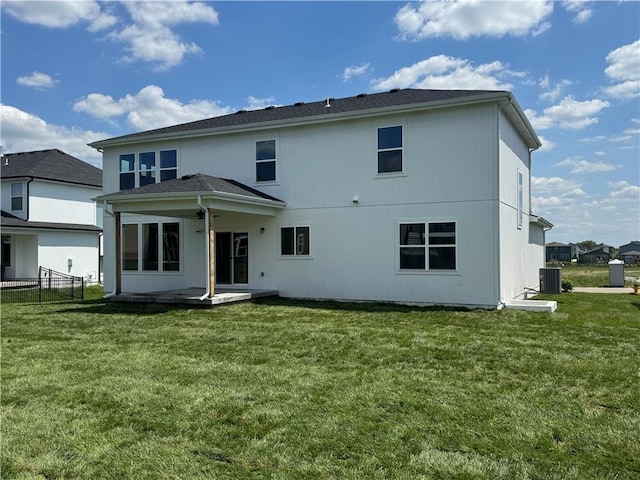 rear view of property featuring a lawn, a patio area, central AC, and fence