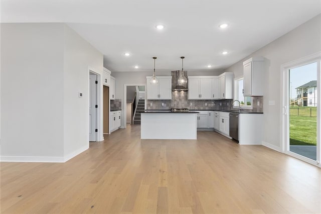 13424 W 178th St, Overland Park, KS 66013 - kitchen with wall chimney exhaust hood, stainless steel dishwasher, dark countertops, tasteful backsplash, and light wood-style flooring
