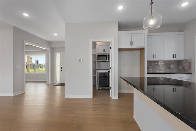 13424 W 178th St, Overland Park, KS 66013 - kitchen featuring beverage cooler, dark countertops, light wood-type flooring, stainless steel microwave, and tasteful backsplash