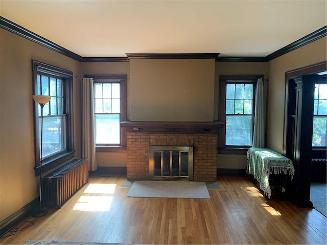 unfurnished living room with ornamental molding, radiator, hardwood / wood-style floors, and a wealth of natural light