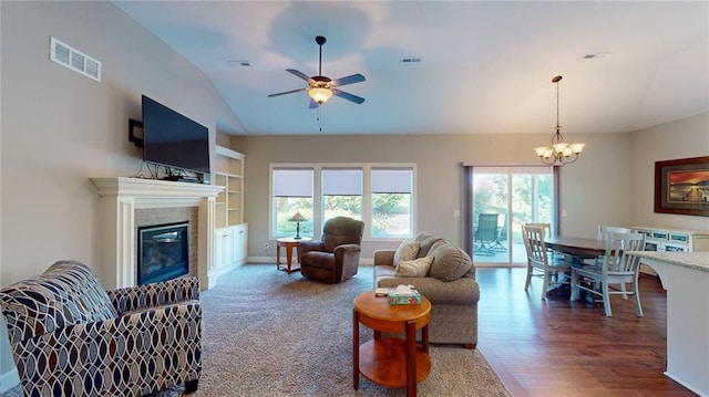 living room with lofted ceiling, wood-type flooring, ceiling fan with notable chandelier, and a healthy amount of sunlight