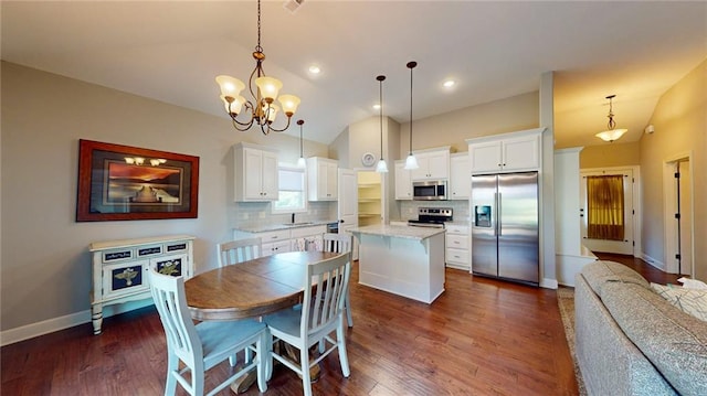 kitchen featuring a kitchen island, decorative light fixtures, appliances with stainless steel finishes, vaulted ceiling, and dark hardwood / wood-style flooring