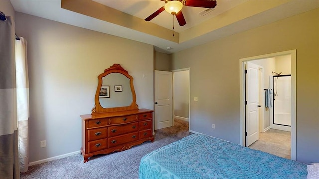 carpeted bedroom featuring ensuite bath, ceiling fan, and a raised ceiling