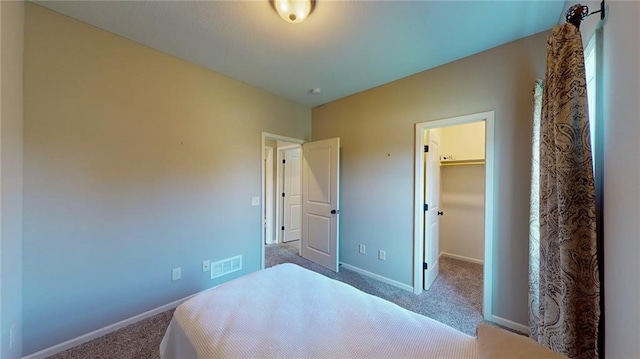 carpeted bedroom with a closet and a spacious closet