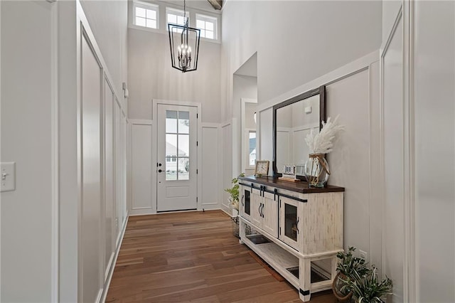 entryway with a notable chandelier, wood-type flooring, and a towering ceiling