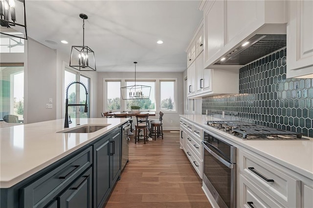 kitchen featuring stainless steel appliances, backsplash, pendant lighting, white cabinets, and custom range hood