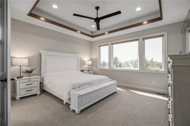 bedroom with a tray ceiling, ceiling fan, and light colored carpet