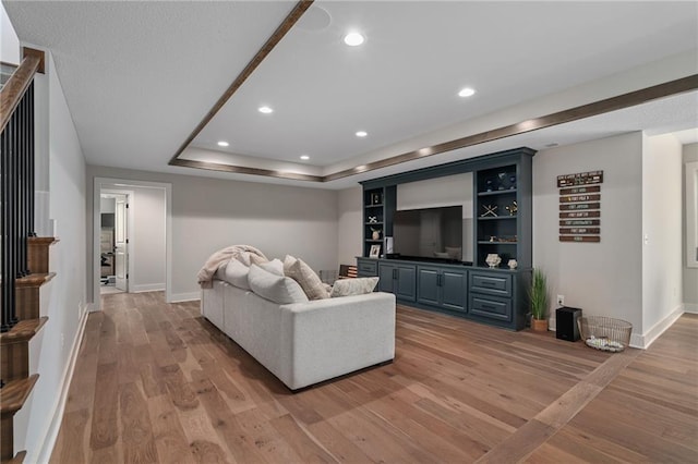 living room featuring a tray ceiling and light hardwood / wood-style floors