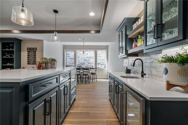 kitchen featuring pendant lighting, sink, wine cooler, light wood-type flooring, and a kitchen island