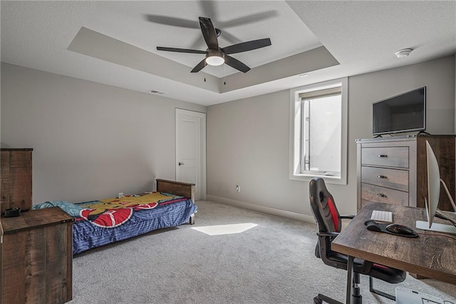 carpeted bedroom with a raised ceiling and ceiling fan