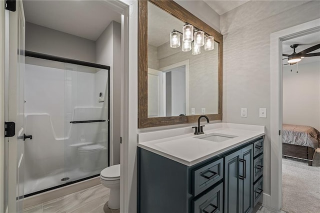 bathroom featuring vanity, toilet, ceiling fan, and a shower with shower door