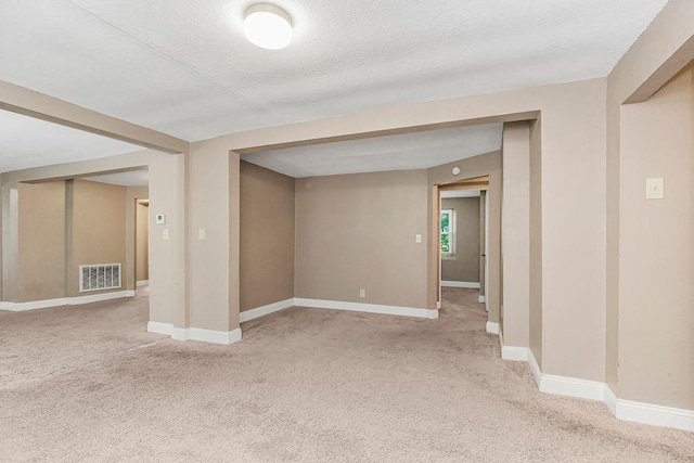 basement featuring a textured ceiling and light colored carpet