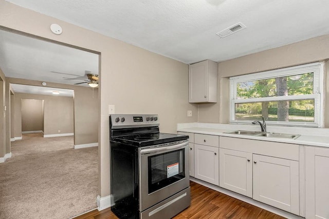 kitchen featuring ceiling fan, white cabinets, sink, stainless steel range with electric stovetop, and dark hardwood / wood-style floors