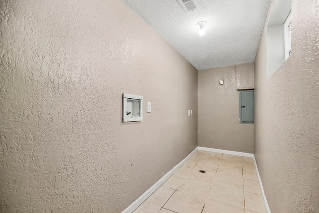 washroom featuring a textured ceiling, hookup for a washing machine, light tile patterned floors, and electric panel