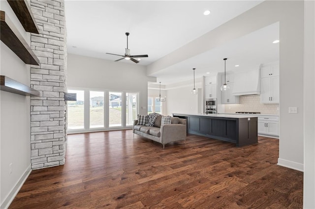 unfurnished living room with ceiling fan with notable chandelier and dark hardwood / wood-style floors