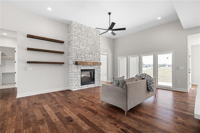 unfurnished living room with a stone fireplace, dark hardwood / wood-style floors, and ceiling fan