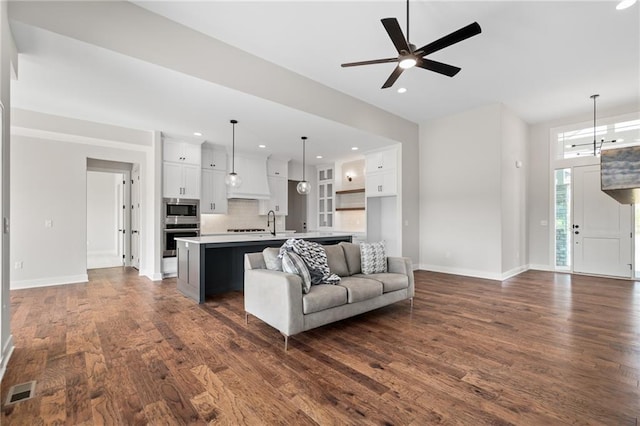 living room with sink, ceiling fan with notable chandelier, and dark wood-type flooring