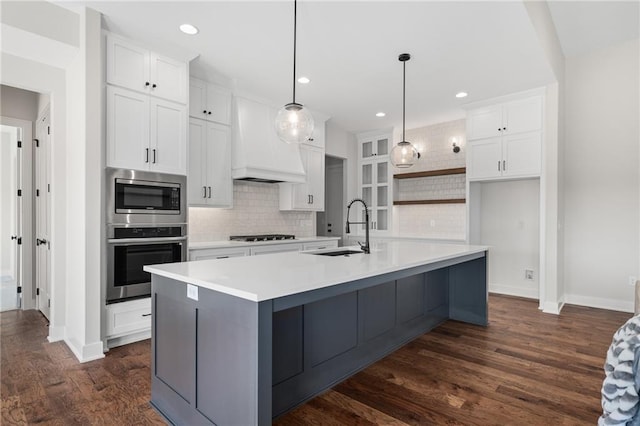 kitchen featuring white cabinetry, a center island with sink, decorative light fixtures, and sink