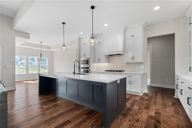 kitchen with a center island with sink, dark wood-type flooring, custom exhaust hood, and white cabinets