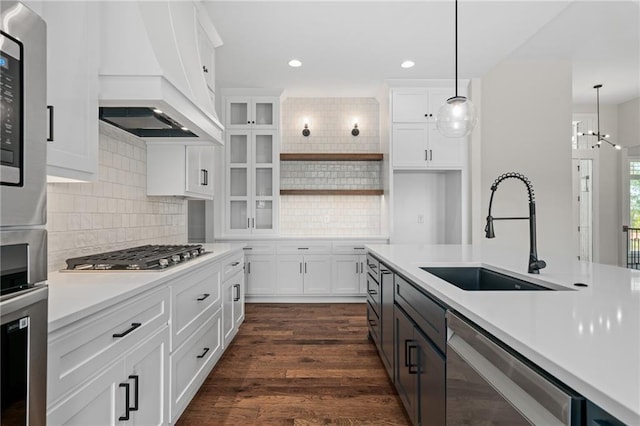 kitchen featuring custom range hood, hanging light fixtures, white cabinets, stainless steel appliances, and sink