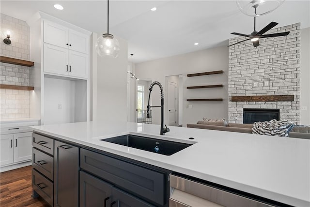 kitchen featuring white cabinets, sink, a fireplace, and dark hardwood / wood-style flooring