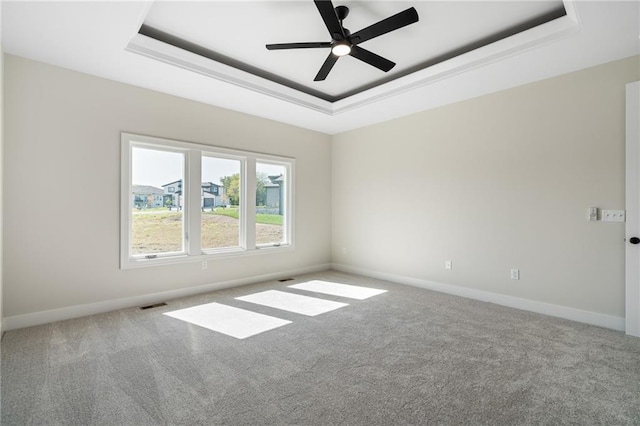 unfurnished room featuring ceiling fan, a tray ceiling, and carpet flooring