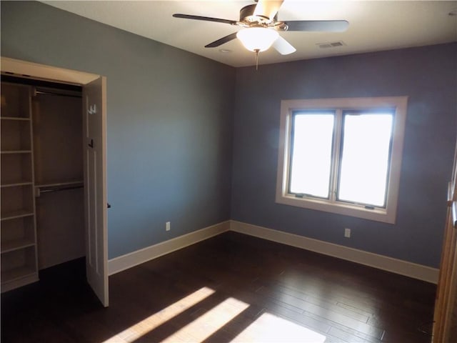 unfurnished bedroom with dark hardwood / wood-style flooring, a closet, and ceiling fan