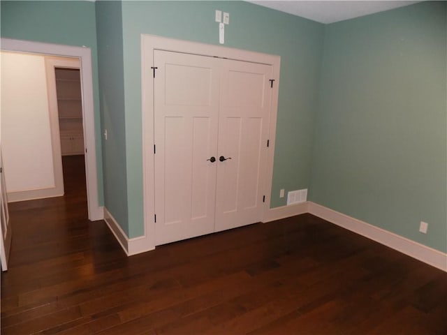 unfurnished bedroom with dark hardwood / wood-style floors and a closet