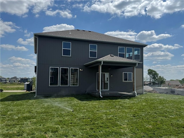 rear view of house featuring cooling unit and a lawn