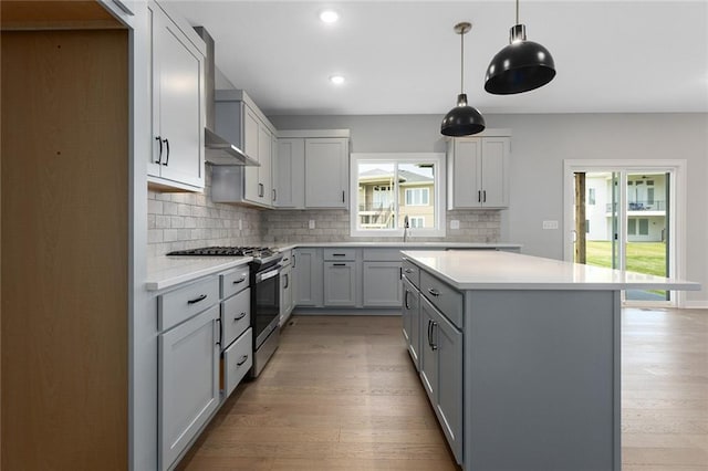 13428 W 178th St, Overland Park, KS 66013 - kitchen featuring stainless steel gas range oven, wall chimney exhaust hood, gray cabinetry, tasteful backsplash, and light wood finished floors
