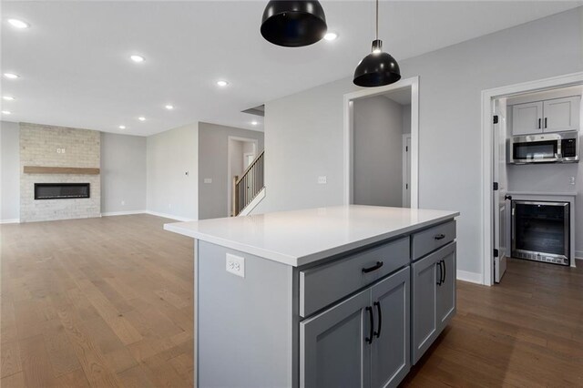 13428 W 178th St, Overland Park, KS 66013 - kitchen featuring wine cooler, stainless steel microwave, gray cabinetry, wood finished floors, and light countertops