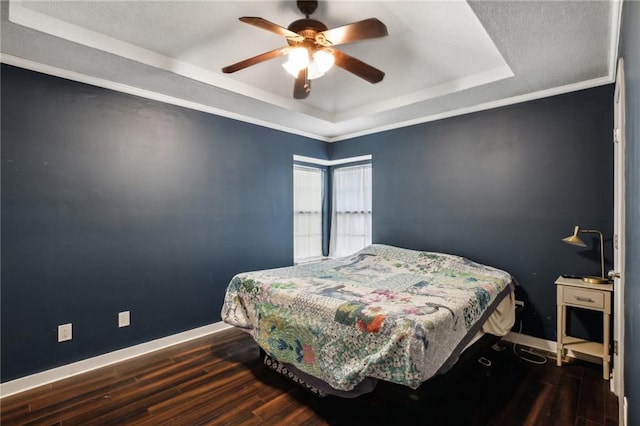 bedroom with ceiling fan, a raised ceiling, crown molding, and dark hardwood / wood-style flooring